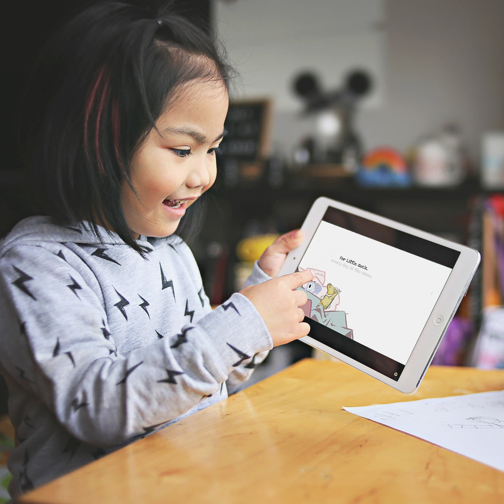 A young reader following an animated story on a tablet